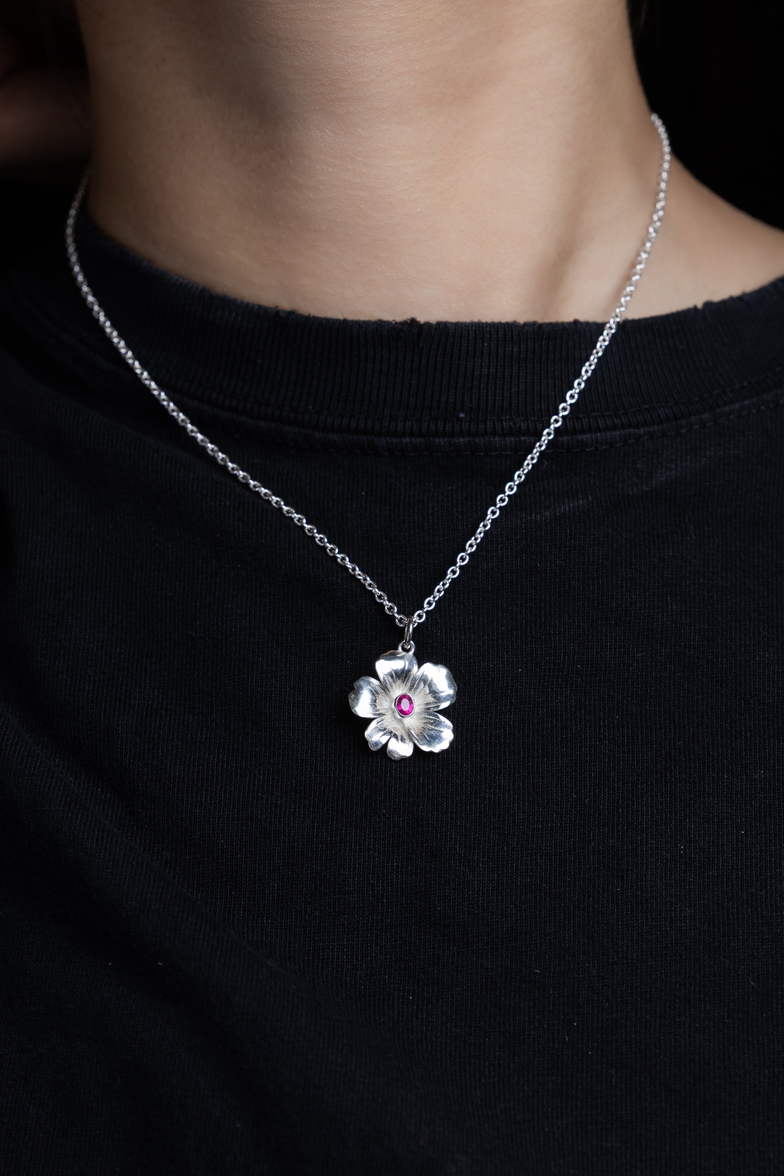 Silver flower-shaped pendant with a red ruby gemstone