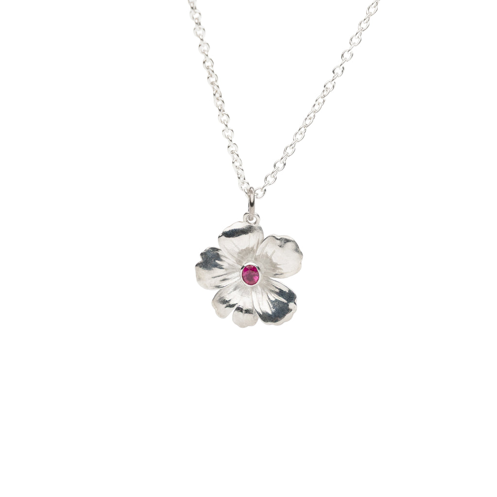 Silver flower-shaped pendant with a red ruby gemstone